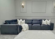 Gray sectional sofa with white pillows in a room with gray walls and a light gray rug.
