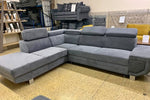 Gray sectional sofa in a furniture store setting with other sofas and decor items.