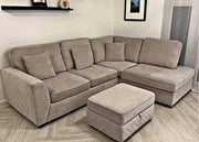 Beige sectional sofa with ottoman in a room with light wood flooring and a neutral wall.