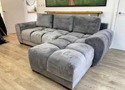 Gray sectional sofa in a room with wooden flooring and a painting on the wall.