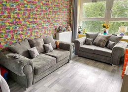 Living room with gray sofas, colorful wall, and large window.