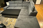 Gray sectional sofa with a coffee table on a wooden floor.