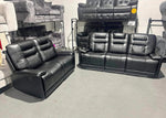 Two black leather recliner sofas in a showroom setting.