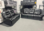 Two black leather recliner sofas in a showroom setting.
