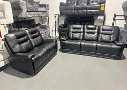 Two black leather recliner sofas in a showroom setting.
