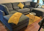 Gray sectional sofa with yellow blanket and pillow in a living room setting