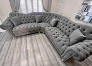 Gray tufted sectional sofa in a room with light wood flooring and white walls.