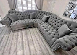 Gray tufted sectional sofa in a room with light wood flooring and white walls.