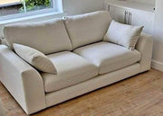Beige sofa in a room with wooden flooring and a window in the background
