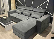 Gray sectional sofa in a living room setting with a geometric wall design.