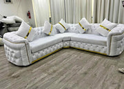 White sectional sofa with gold accents in a room with curtains and a fire extinguisher.