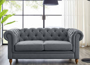 Gray tufted sofa in a room with large windows and a lamp.