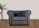 Gray tufted armchair in a room with a plant and wooden floor.