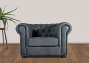 Gray tufted armchair in a room with a plant and wooden floor.