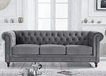 Gray tufted sofa in a room with white walls and light wood flooring.