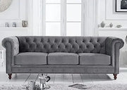 Gray tufted sofa in a room with white walls and light wood flooring.