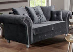Gray velvet sofa in a living room setting with wooden floor and window in the background
