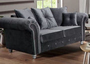Gray velvet sofa in a living room setting with wooden floor and window in the background