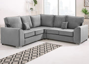 Gray sectional sofa in a living room with a patterned rug and plants.