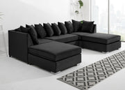 Black sectional sofa in a living room with a patterned rug.