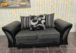 Gray sofa with decorative pillows against a patterned wall.