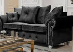 Gray velvet sofa in a living room setting with a coffee table and decorative items.