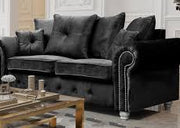 Gray velvet sofa in a living room setting with a coffee table and decorative items.