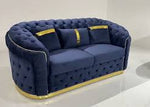 Blue tufted sofa with gold accents on a white background