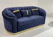 Blue tufted sofa with gold accents on a white background