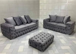 Gray tufted sofa set with matching ottoman on a patterned floor.