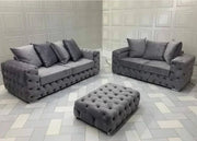 Gray tufted sofa set with matching ottoman on a patterned floor.