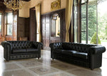 Two black leather sofas in a luxurious room with wooden paneling and large windows.