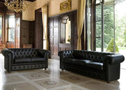 Two black leather sofas in a luxurious room with wooden paneling and large windows.